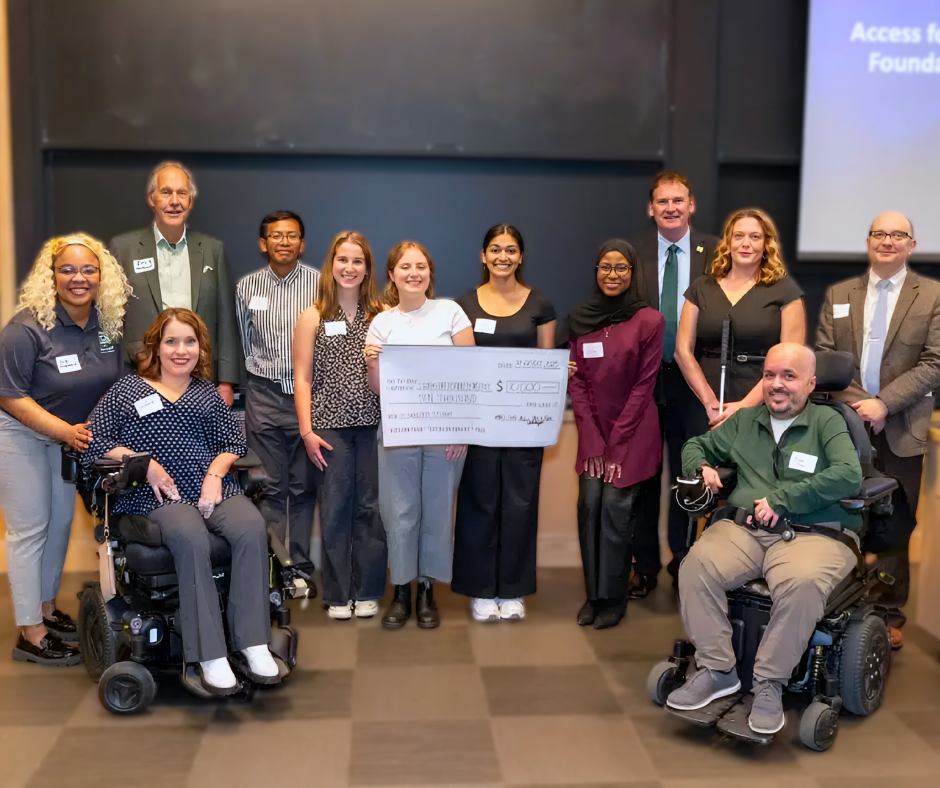 A group of 12 people smile during a check presentation.