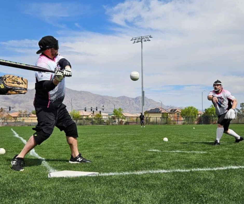 A player wearing a blindfold waits for the pitch midway through the air during BeepBall batting practice.