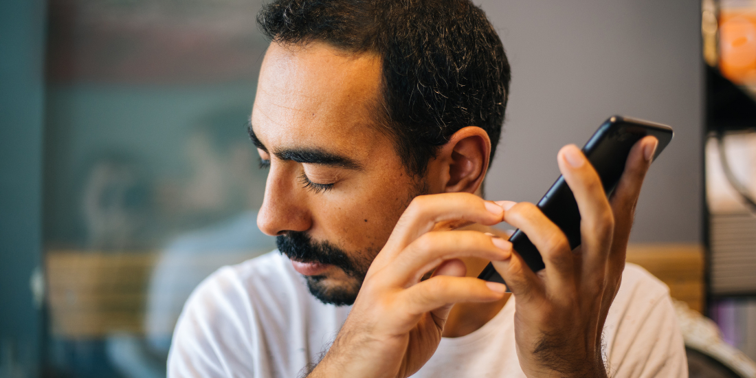 Blind person listening to a text on their phone.