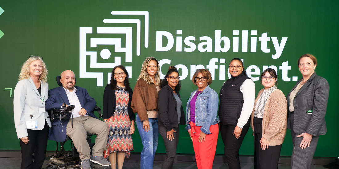 Group of Starkloff staff, board members, and attendees smiling onstage. The background is Starkloff’s Disability Confident logo.